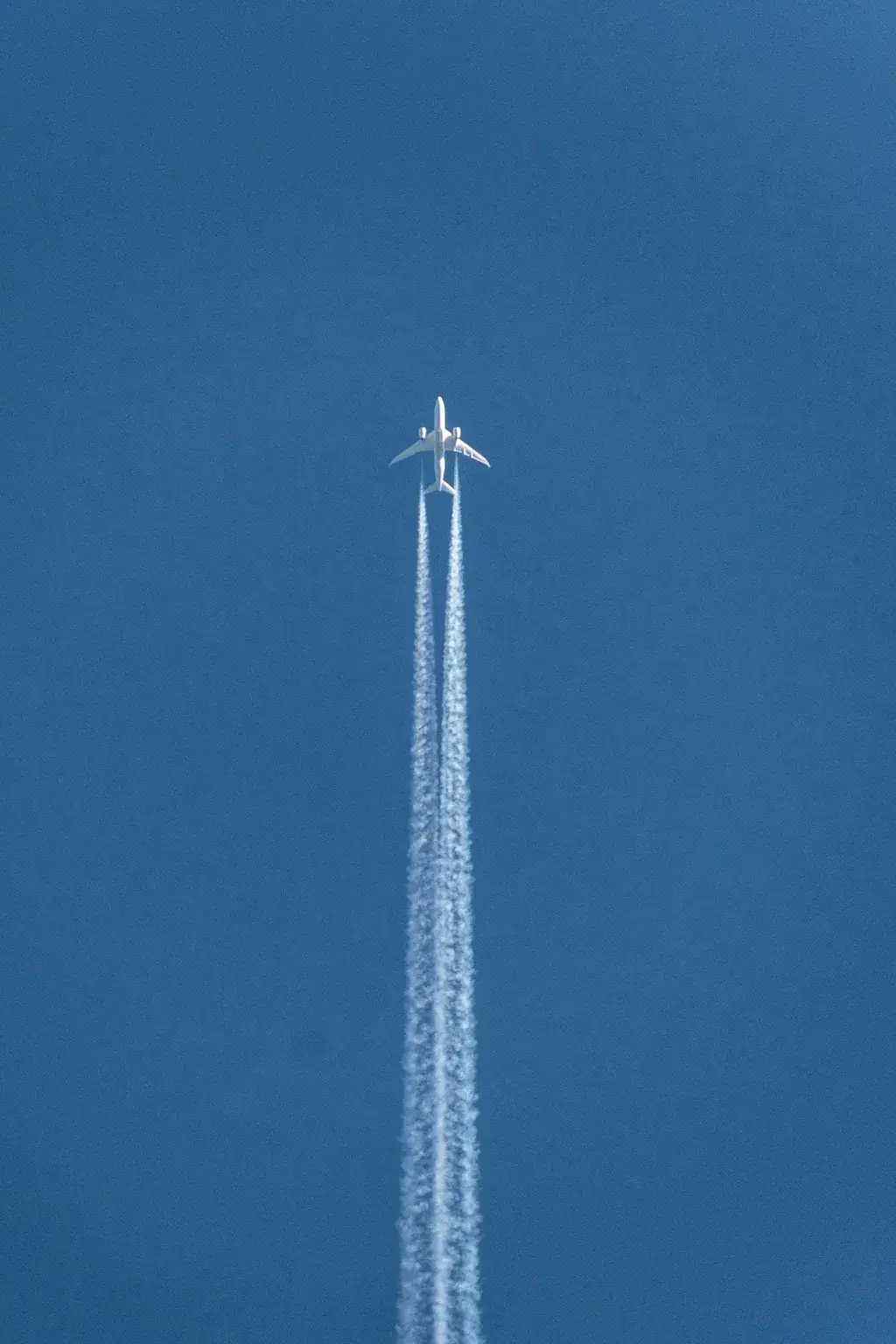 Airplane in flight leaving a trail, viewed from below