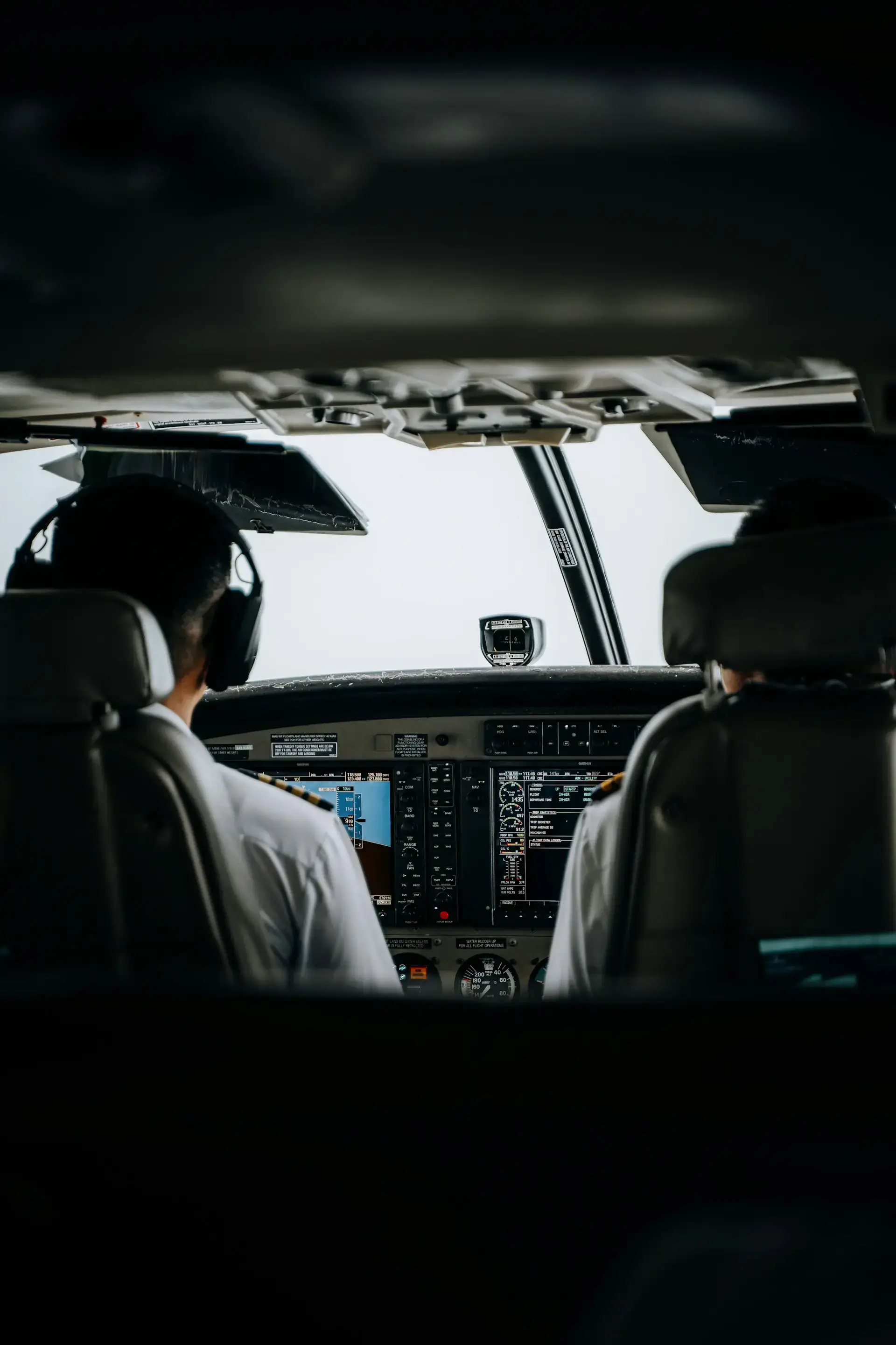 Pilots seated in a cockpit, viewed from behind