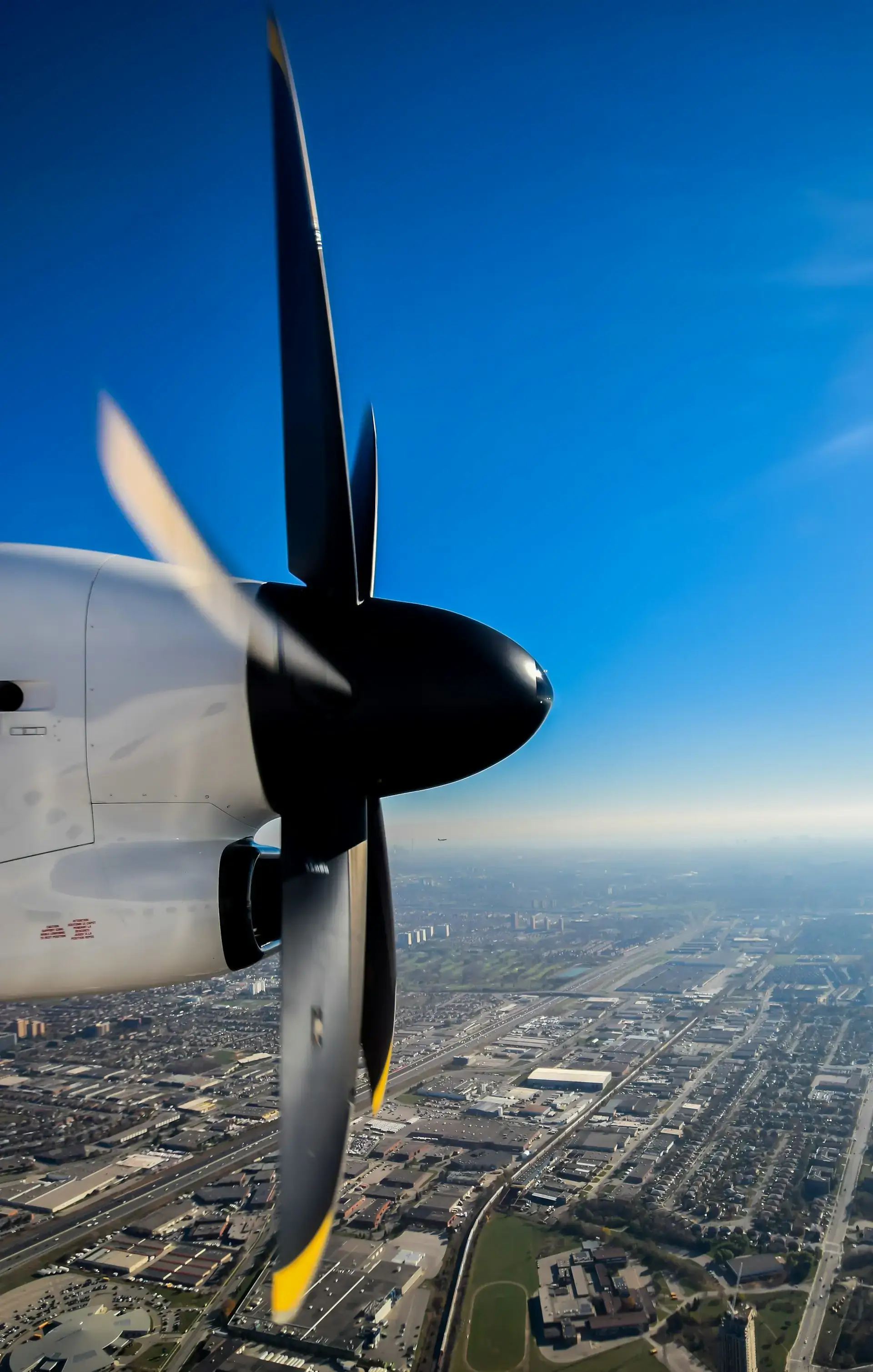 Side view of a turboprop engine in flight over a city