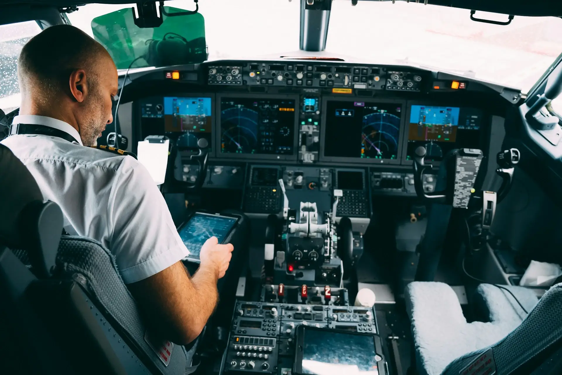 Pilot holding a document in a cockpit, viewed from behind