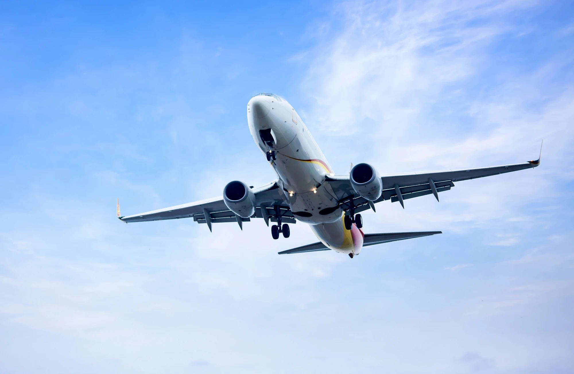 Airplane flying through a blue sky with clouds