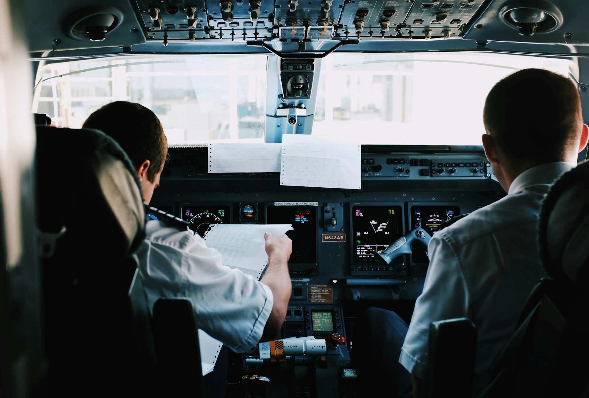 Pilots seated in a cockpit, viewed from behind